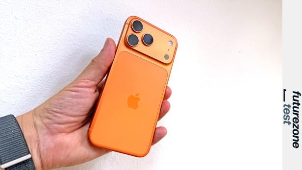 Ein orangefarbenes iPhone 17 Pro Max wird in der Hand gehalten.