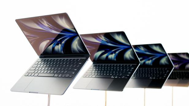 Mehrere geöffnete MacBooks stehen in einer Reihe vor einem weißen Hintergrund.