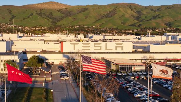 Vor einer Tesla-Fabrik wehen die amerikanische Flagge und die Flagge Kaliforniens.