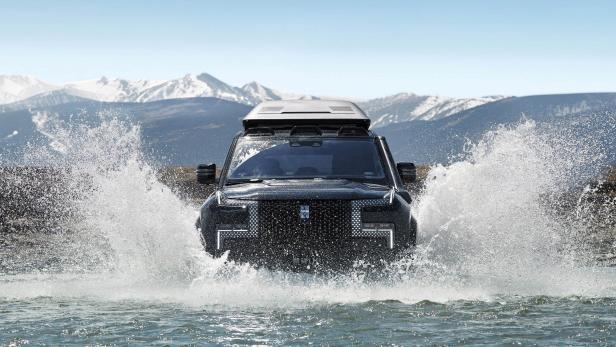 Ein schwarzer Geländewagen fährt durch ein Gewässer.