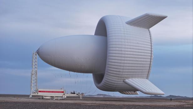 Ein großer, weißer, ungewöhnlich geformter Windrad-Prototyp steht in einer kargen Landschaft.