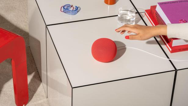 Neuer Google-Lautsprecher in Rot mit Hand, die in die Richtung greift