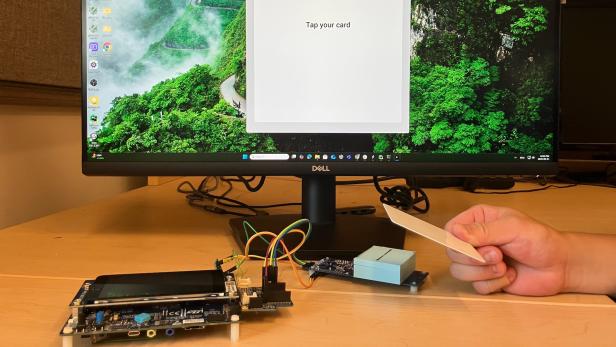 Ein Bildschirm und davor der Prototyp des NFC-Terminals