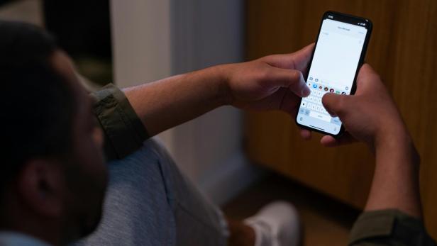 Ein Mann hält ein Handy in der Hand, eine Messenger-App ist geöffnet