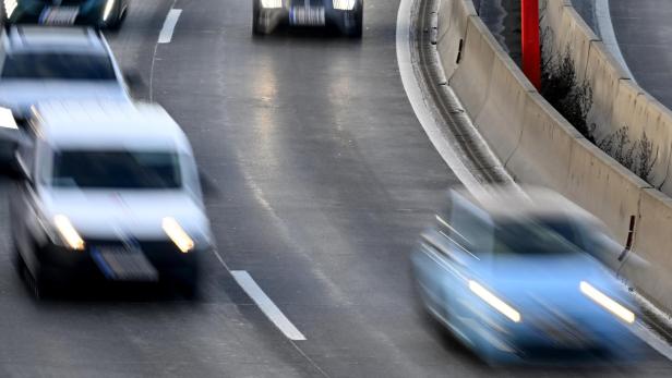 Autos fahren mit eingeschalteten Scheinwerfern auf einer Autobahn.