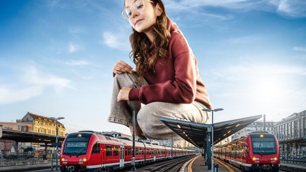 eine junge Frau hockt zwischen zwei Zügen 