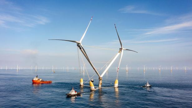 Die schwimmende Offshore-Windkraftanlage OceanX von Mingyang mit zwei V-förmig angeordneten Rotoren wird von mehreren Schiffen auf dem Meer begleitet.
