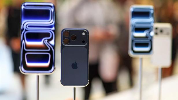 Mehrere neue Smartphones mit auffälligen Kameras und leuchtenden Displays stehen nebeneinander auf Ständern.