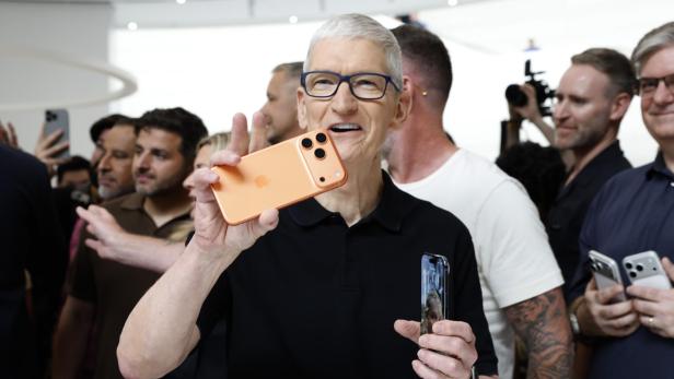 Apple-CEO Tim Cook hält ein iPhone in der Hand