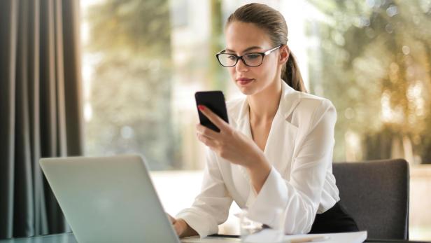 Eine Frau schaut während der Arbeit auf ihr Smartphone.