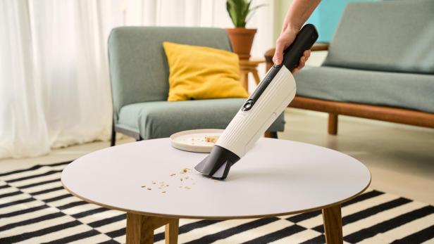Kobold Handstaubsauger saugt Brösel am Beistelltisch auf 