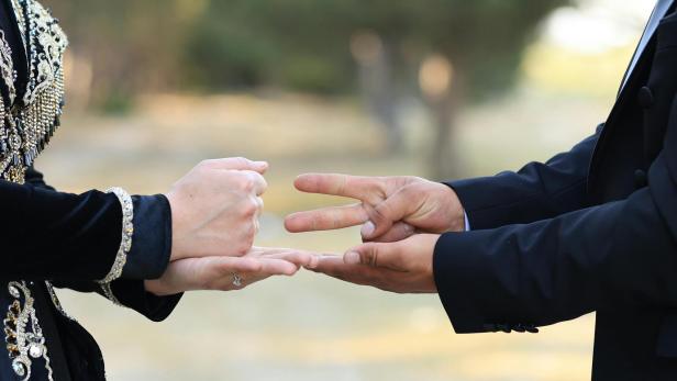 zwei Menschen spielen Schere Stein Papier, die linke Person zeigt Stein, die rechte Schere