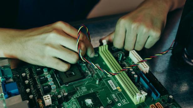 Eine Person schraub am Innenleben eines Computers herum