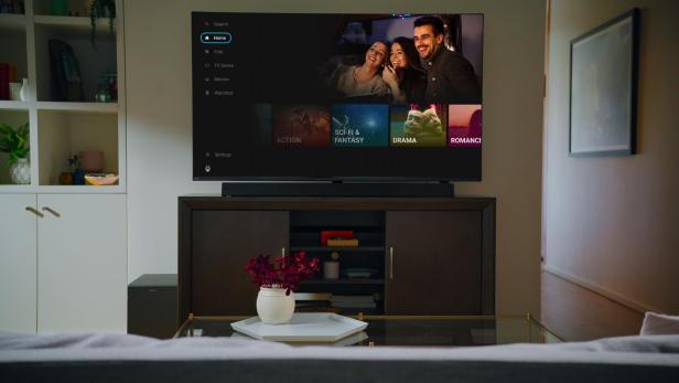 Ein moderner Fernseher mit TiVo-Oberfläche zeigt verschiedene Film- und Serienkategorien in einem gemütlichen Wohnzimmer.
