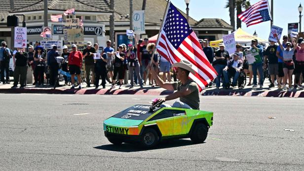 Ein Mann fährt auf einem Spielzeuggefährt und schenkt eine US-Flagge