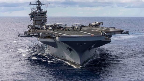 Flugzeugträger mit mehreren Flugzeugen auf dem Deck fährt durch das offene Meer.