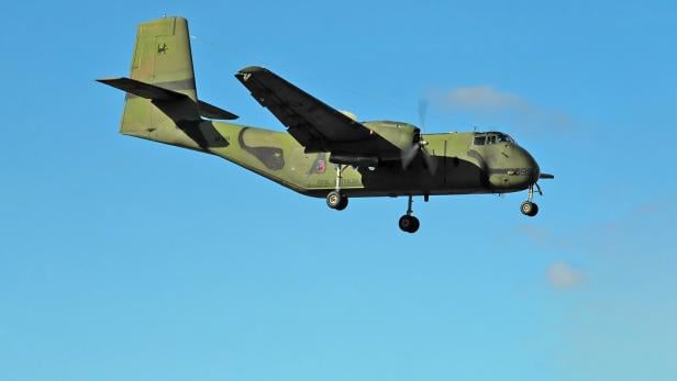 Eine de Havilland Canada DHC-4 Caribou Transportmaschine fliegt vor blauem Himmel