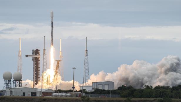 Eine Rakete startet mit hellem Feuer und Rauch von einer Startrampe in den Himmel.