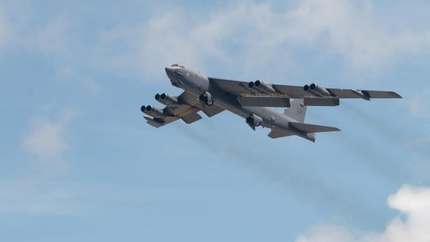 Eine B-52H fliegt am Himmel mit ausgefahrenem Fahrwerk und sichtbaren Triebwerken.