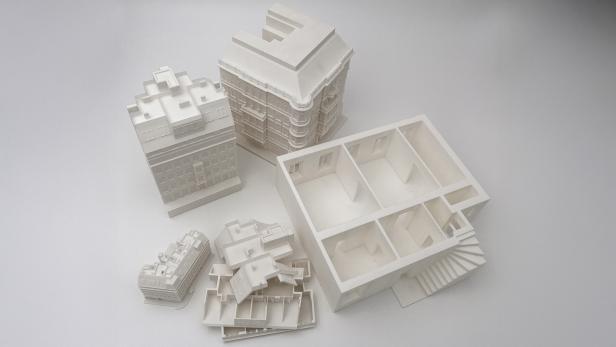 Mehrere detailreiche, weiße 3D-gedruckte Architekturmodelle auf weißem Untergrund.