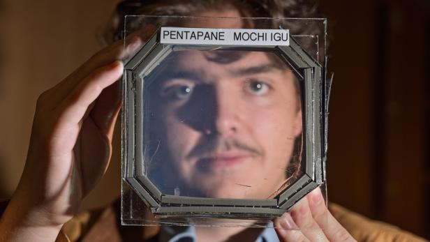 Ein Mann hält eine fast transparente MOCHI-Platte vor sein Gesicht