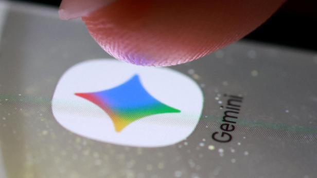 Ein Finger berührt das Symbol einer App mit buntem Stern und der Aufschrift „Gemini“ auf einem Smartphone-Bildschirm.