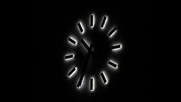 große Wanduhr mit belezchteten Zeigern im Dunkeln