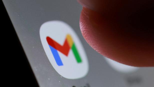Ein Finger tippt auf das Gmail-Symbol auf einem grauen Bildschirm.