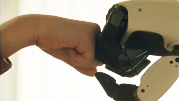 Menschliche Hand macht Fistbump mit Roboterhand