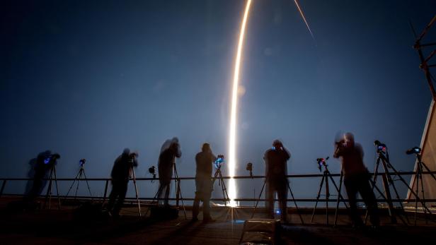 Fotografen beobachten und fotografieren den Start einer Rakete in der Nacht.