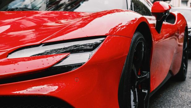 Roter Sportwagen mit glänzendem Lack und Wassertropfen auf der Motorhaube.