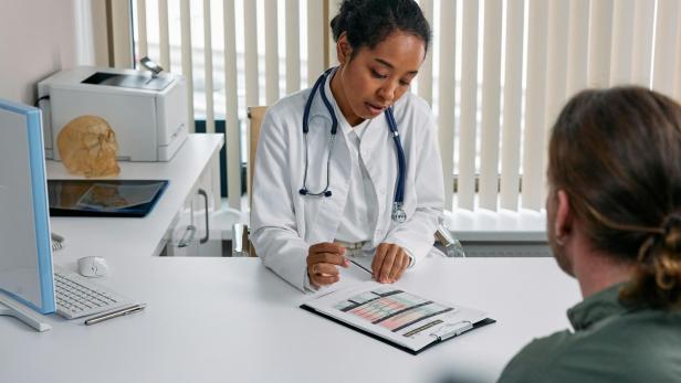 Ärztin bespricht medizinische Testergebnisse mit einem Patienten im Sprechzimmer.