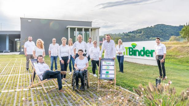 Gruppe von Mitarbeitenden vor dem ITBinder-Gebäude und einem großen Firmenschild im Grünen.