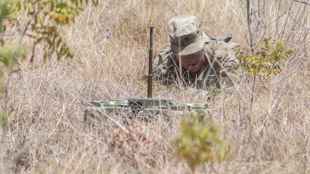 Soldat in Tarnuniform platziert XM204-Mine im trockenen Grasland.