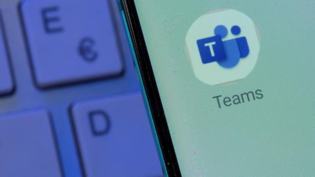 Auf einem Smartphone-Bildschirm ist das Microsoft Teams-Symbol neben einer Computertastatur zu sehen.