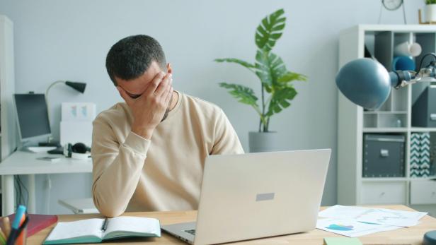 Mann sitzt verzweifelt vor Laptop 