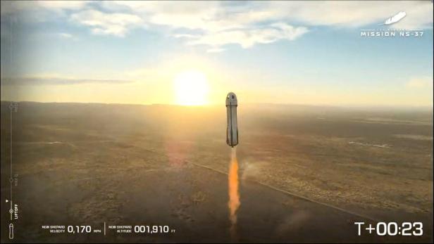 Eine Rakete steigt bei Sonnenaufgang mit orangefarbenem Abgasstrahl über eine weite Landschaft auf.