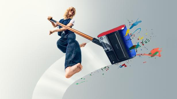 Person wischt mit Dyson PencilWash farbige Flecken auf hellem Boden.