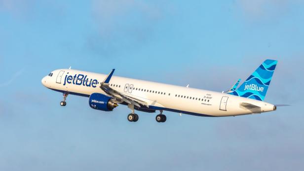 Ein JetBlue Airbus A321neo startet vor blauem Himmel.