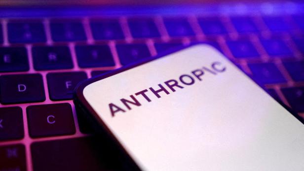 Ein Smartphone mit dem Schriftzug „ANTHROPIC“ liegt auf einer beleuchteten Tastatur.