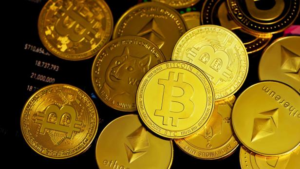 Goldene Münzen mit Symbolen von Bitcoin, Ethereum und Dogecoin auf schwarzem Hintergrund.