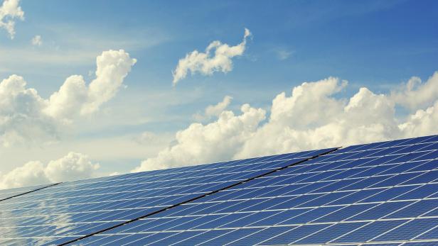 Solarpanels vor einem blauen Himmel mit weißen Wolken.