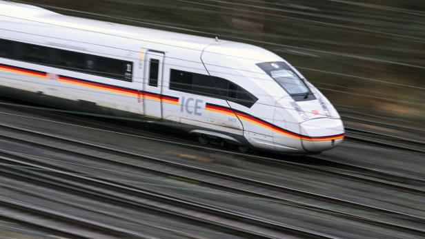 Ein weißer ICE-Zug rast auf Gleisen dahin.