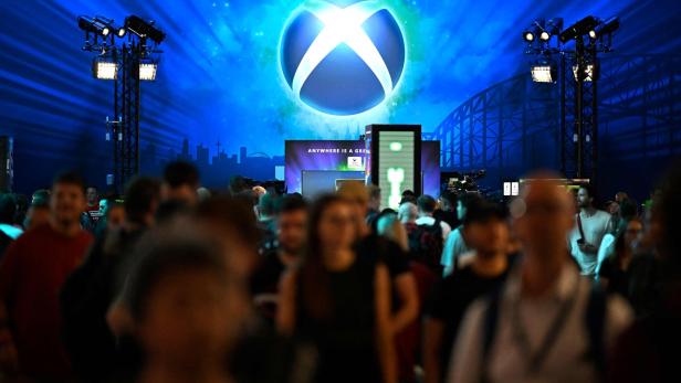 Eine Menschenmenge steht vor einer großen, blau beleuchteten Xbox-Bühne auf einer Messe.