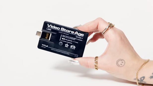 Eine Hand hält einen schwarzen "Video Store Age" USB-Stick.