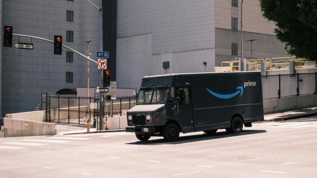 Ein Amazon-Prime-Lieferwagen fährt durch eine leere Straßenkreuzung in der Stadt.
