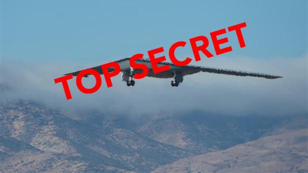 Ein B-21 Stealth-Bomber fliegt vor Bergen, darüber steht in Rot „TOP SECRET“.