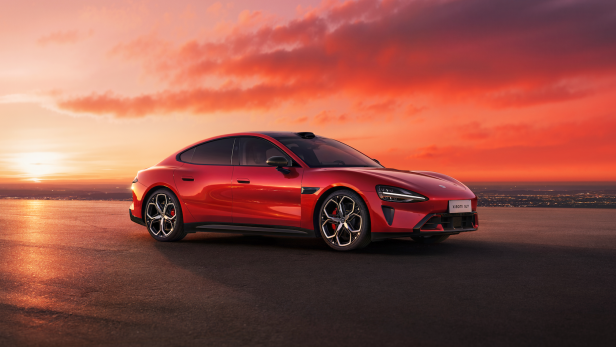 Rotes Elektroauto auf offener Straße vor Sonnenuntergang und weitem Horizont.