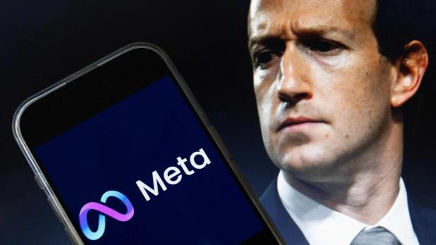 Ein Smartphone zeigt das Meta-Logo, während im Hintergrund das Gesicht von Mark Zuckerberg zu sehen ist.