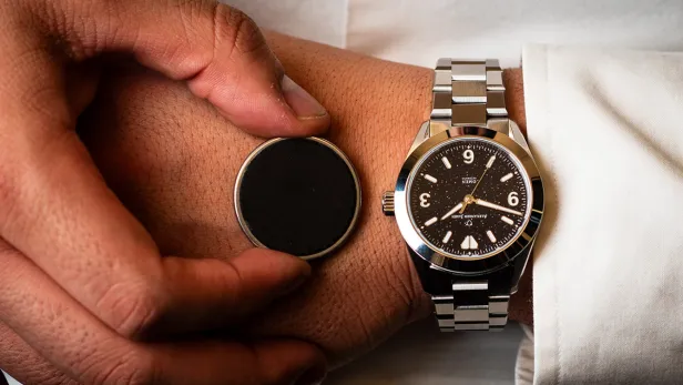 Das münzgroße Gerät neben einer klassischen Uhr.